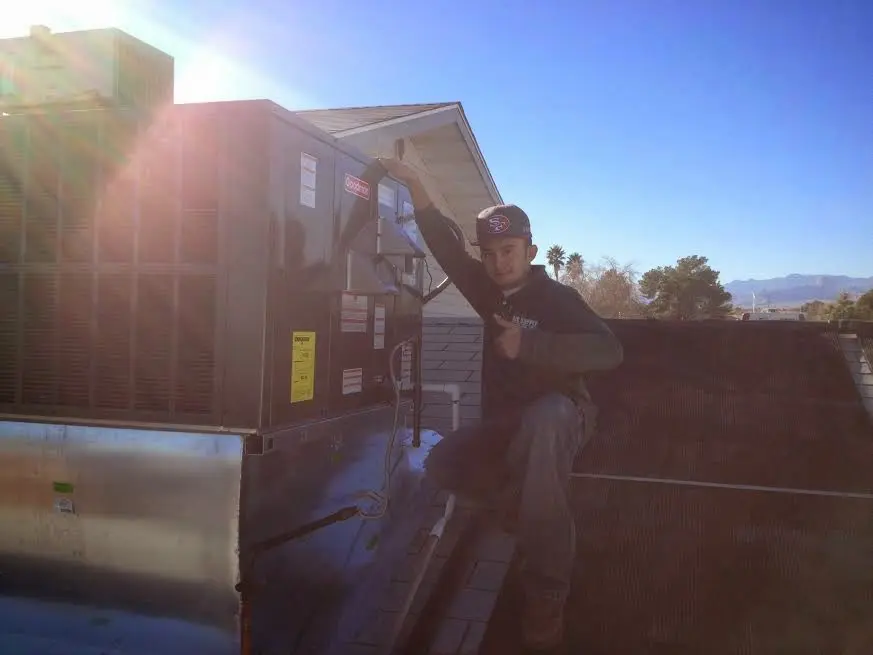 HVAC technician performing AC Tune-Up on a rooftop unit in Joshua Tree